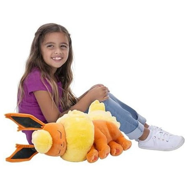 Peluche Pyroli 45 cm posée près d’un enfant pour illustrer la taille et le volume de ce compagnon de jeu.